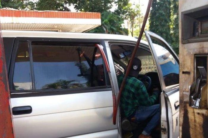 Sebuah Toyota Kijang mengisi Bbm dengan cara tidak lazim, lewat jendela ke dalam kabin