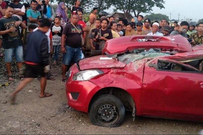 Warga mengerumuni mobil Datsun GO yang ringsek ditabrak KA Dhoho di perlintasan kereta api  tanpa palang pintu di Jombang, Kamis (12/9/2019) 