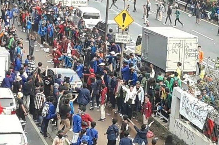 Ilustrasi massa unjuk rasa yang melakukan vandalisme terhadap mobil berplat merah