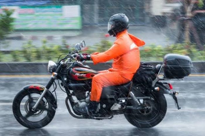 Ilustrasi naik motor saat hujan yang dianjurkan, pakai jas hujan setelan, helm full face dan sepatu