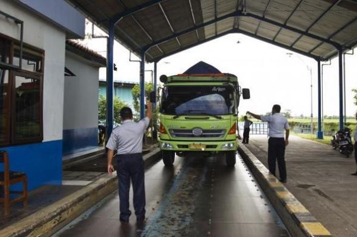 Ilustrasi petugas melakukan penimbangan truk di jembatan timbang.