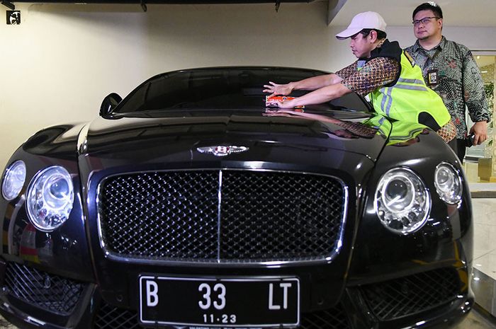 Fungsional pada Koordinasi Supervisi dan Pencegahan Korwil 3 Komisi Pemberantasan Korupsi (KPK) Friesmount Wongso (kanan) mengamati Petugas Samsat Jakarta Utara Kukun Kurnadi menempelkan stiker 'Objek Pajak' pada mobil mewah saat razia supervisi pencegahan pajak mobil mewah di Apartemen Regatta, Jak