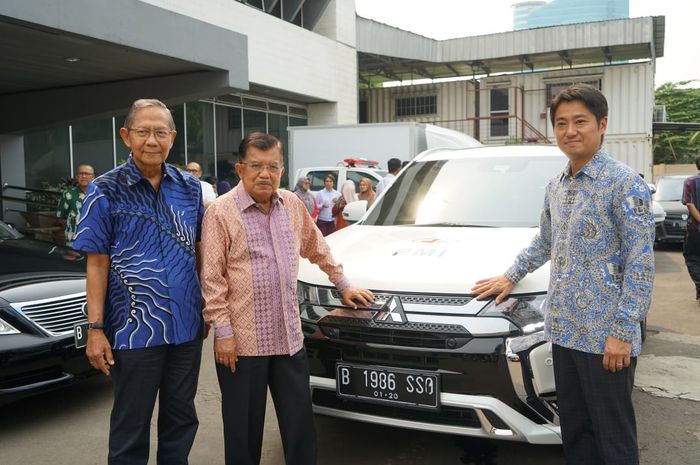 Presiden Direktur PT Mitsubishi Motors Krama Yudha Sales Indonesia, Naoya Nakamura beserta pelaksana harian PMI, Ginandjar Kartasasmita dan Ketua Umum PMI Jusuf Kalla saat menyerahkan Outlander PHEV