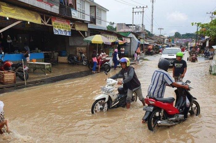 Ilustrasi pengendara motor melewati jalan yang banjir