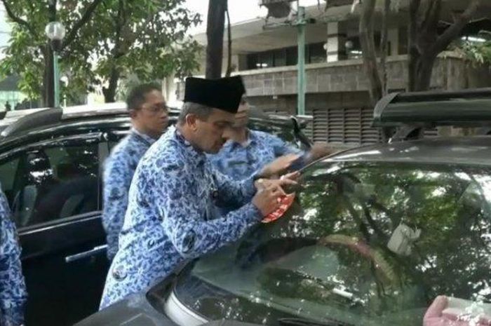 Walikota Jakarta Timur sedang menempelkan stiker penunggak pajak pada mobil ASN 