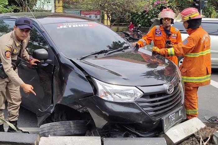 Petugas Satpol PP Bubutan mengevakuasi Daihatsu Xenia pengantar pesanan catering yang hantam pembatas jalan hingga bodi depan mobil ringsek, Rabu (25/12/2019).  