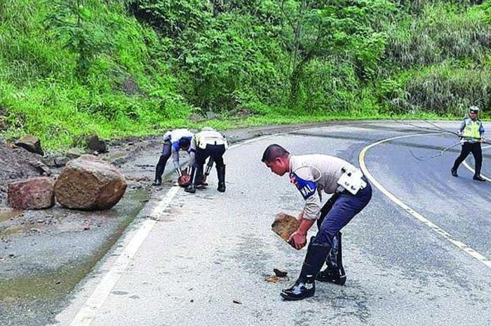Anggota Satlantas Polres Bireuen, Senin (30/12/2019) memindahkan tanah yang jatuh ke badan jalan di KM 27 Bireuen-Takengon.