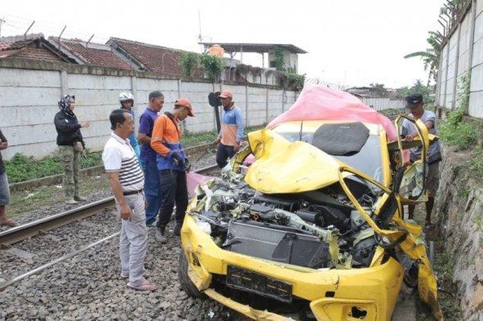 Honda Brio warna kuning ringsek setelah beradu lawan kereta api