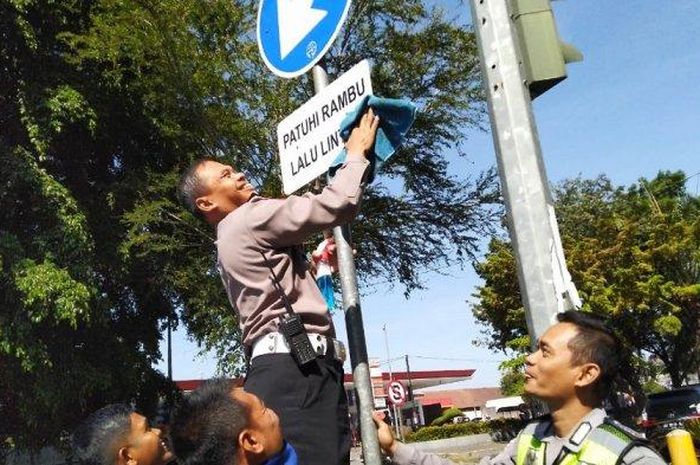 Ilustrasi : Kasat Lantas Kompol Busroni saat Membersihkan rambu lalu lintas. 