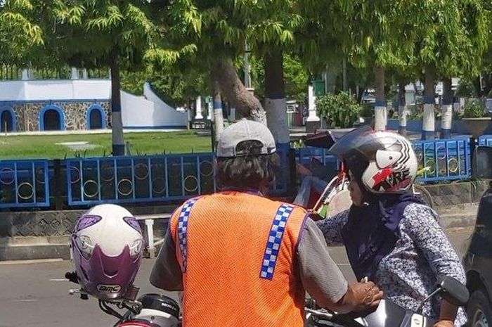 Seorang juru parkir Alun- alun Kota Tegal membantu pengendara mengeluarkan motornya  