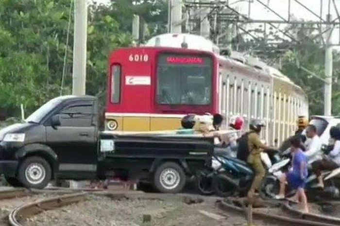 Suzuki Mega Carry terjebak di atas perlintasan kereta api saat sebuah KRL melaju mendekat