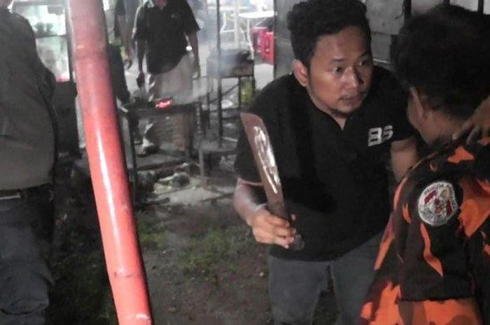 Personel Tim Rajawali Polrestro Jakarta Timur saat menunjukkan golok yang digunakan Inam Firmansyah (baju oren) untuk melukai putranya di Jatinegara, Minggu (9/2/2020). 