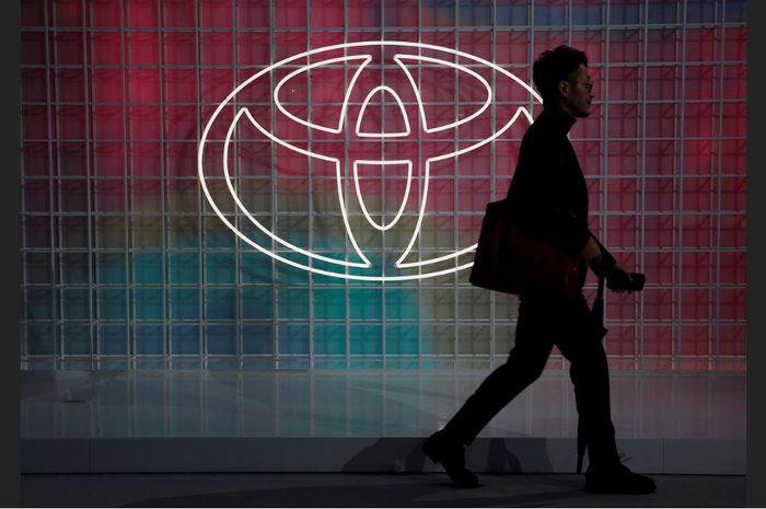 Seorang pria berjalan melewati logo Toyota