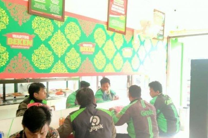 Para pengendara ojek daring menyantap makanan di warteg milik Sonny Mahendra pada Jumat (27/03/2020).