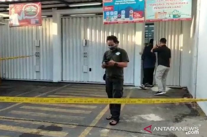 Polisi berseragam bebas dari Polsek Duren Sawit, Jakarta Timur, memasang garis polisi di lokasi kejadian perampokan minimarket, Kamis (16/4/2020) dini hari. 