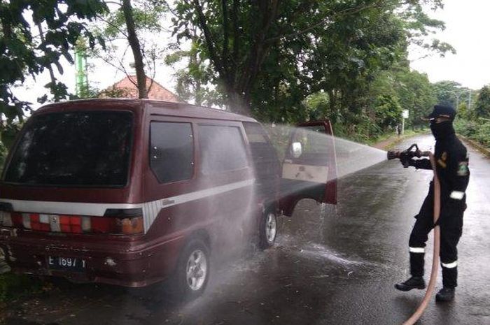  Petugas Damkar Kuningan menyemprotkan cairan disinfektan ke minibus berisi mayat di Jalan Soekarano, Lingkungan Perum Korpri, Kecamatan Kuningan, Sabtu (18/4/2020).