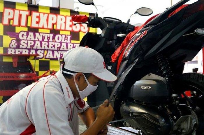 Ilustrasi teknisi AHASS menggunakan masker saat menyervis motor 