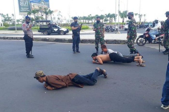 Remaja pelanggar PSBB Makassar ditangkap petugas TNI dan Polri di sekitar Jl Metro Tanjung Bunga, Makassar, Sulsel, Senin (27/4/2020). Mereka dihukum merayap di jalanan.