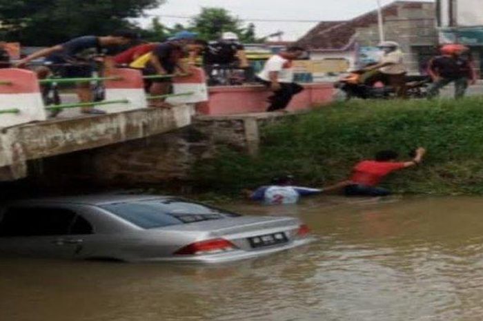 Mobil sedan Mitsubishi Lancer nyemplung ke sungai di Madiun karena berusaha menghindari agar tak menabrak pengendara motor yang belok mendadak. 