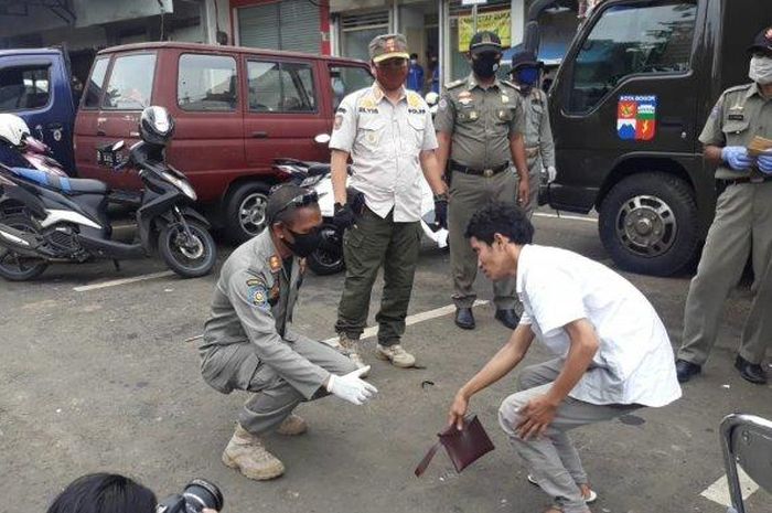 Petugas Satpol PP Kota Bogor memberikan penindakan kepada pelanggar PSBB yang terbukti tidak menggunakan masker. 