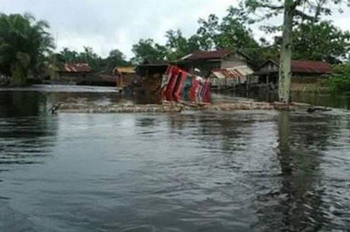Sebuah mobil truk diesel membawa buah kelapa sawit terbalik saat nekat menerobos banjir, Kamis (30/4/2020).  