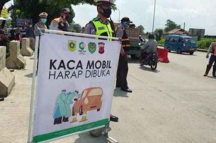 Petugas gabungan mengawasi pengendara yang melintas di check point PSBB Kabupaten Bogor di Cigombong yang berbatasan dengan Cicurug, Kabupaten Sukabumi, Rabu (29/4/2020).  