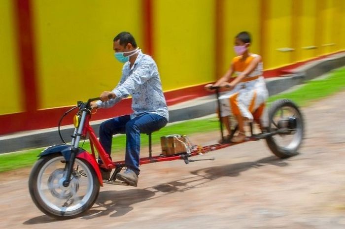 Partha Saha dan sepeda temuannya yang mematuhi aturan jaga jarak selama pandemi virus corona.(AFP/Abhisek Saha)