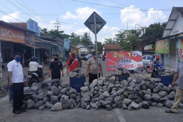 Warga dan Polisi menutup jalur alternatif Jember-Lumajang-Surabaya di Desa Jatiroro Kecamatan Sumberbaru Jember memakai batu