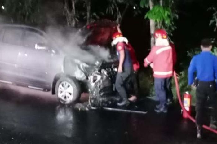 Petugas Damkar Kota Madiun melakukan pembasahan terhadap Toyota Kijang Innova yang terbakar di Ring-road Barat, Kota Madiun, Senin (11/5/2020) 