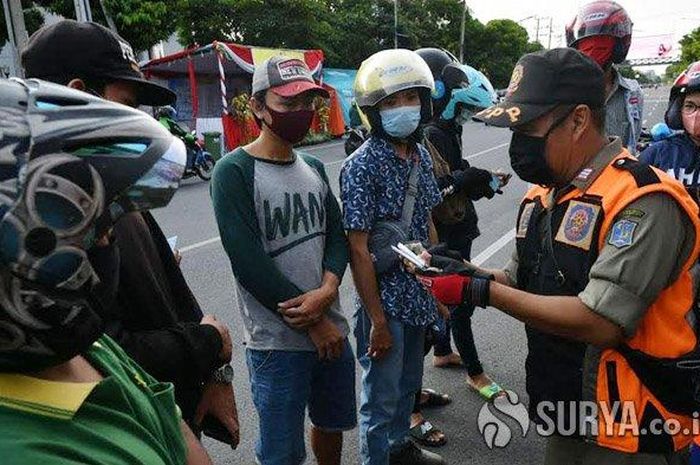 Petugas sedang mendata pelanggar PSBB yang masuk Kota Surabaya melalui Bundaran Waru, Sabtu (2/5/2020).  Tak lama lagi PSBB juga akan diterapkan di Malang Raya.