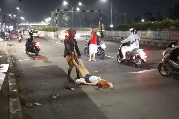 Seorang pedagang mencoba memindahkan wanita yang tak diketahui namanya yang tergeletak di jalan sembari merontah-ronta dan meracau sendirian di Jalan Pasar Minggu Raya, Jakarta Selatan, Kamis (14/5/2020).  