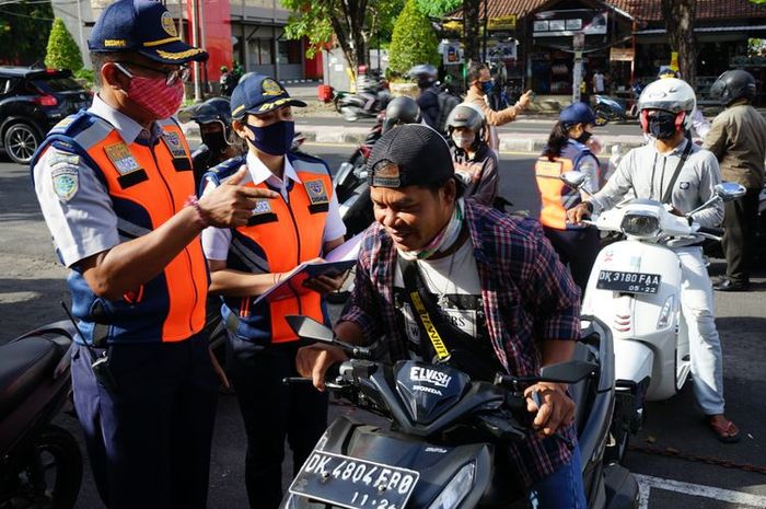 Petugas pos pemeriksaan PKM Denpasar memeriksa pengendara