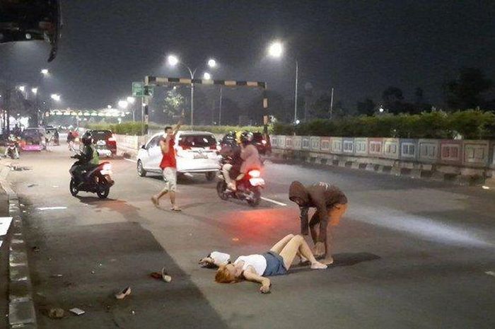 Seorang pedagang mencoba memindahkan wanita yang tak diketahui namanya yang tergeletak di jalan sembari merontah-ronta dan meracau sendirian di Jalan Pasar Minggu Raya, Jakarta Selatan, Kamis (14/5/2020). (Warta Kota/Vini Rizki Amelia)