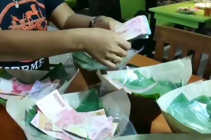 Nasi bungkus yang diselipi dengan beberapa uang berjumlah besar