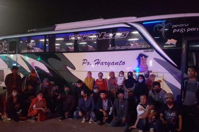 Saat petugas memeriksa kesehatan para penumpang tiga bus travel gelap yang terjaring razia Petugas PJR Ditlantas Polda Jatim saat melintas di Pos Check Point Tol Surabaya-Mojokerto, KM 740/A, Senin (18/5/2020) malam.  