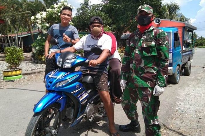 Pengendara roda dua yang melintas di Posko Covid-19 perbatasan antara Desa Bakti dengan Desa Lampuara, Kecamatan Ponrang Selatan, Kabupaten Luwu, Sulawesi Selatan, didapati Babinsa mengenakan masker dari batok tempurung kelapa, Kamis (21/05/2020)