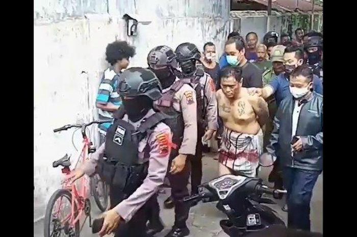 Pria penuh tato di sekujur tubuh dihajar massa sebelum dibawa polisi bersenjata lengkap. Kejadian di lingkungan RW 1, Kelurahan Kadipiro, Kecamatan Banjarsari, Kota Solo, Senin (25/5/2020). 