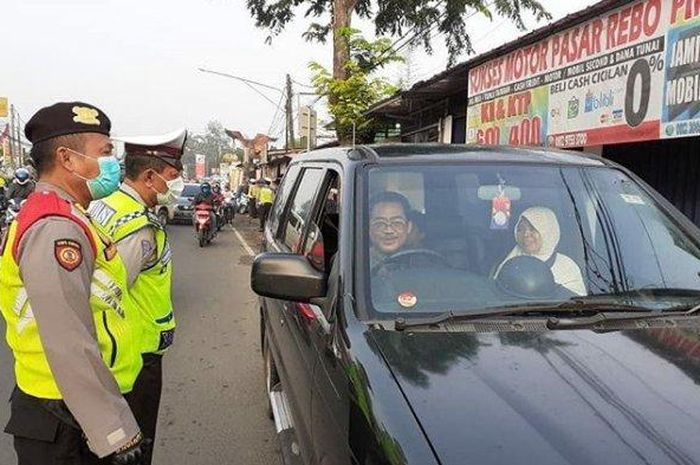 ILUSTRASI: Personel Satlantas Polrestro Jakarta Timur saat menegur pengemudi mobil pribadi yang tidak mengenakan masker di cek poin PSBB Pasar Rebo 