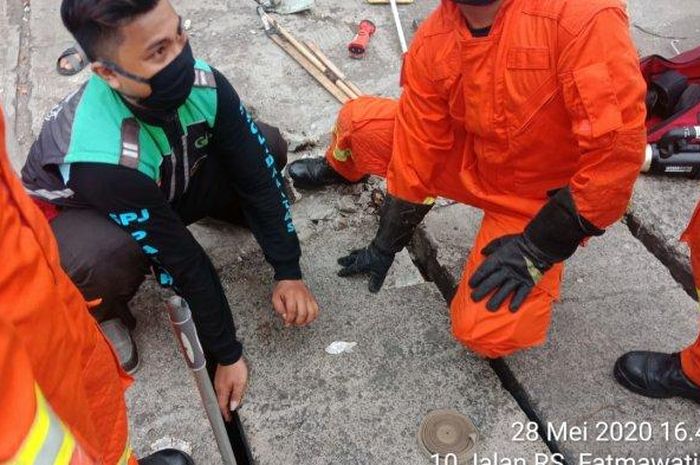 Petugas damkar mengambil ponsel Xiaomi milik Ricky yang terjatuh di saluran air di Jalan RS Fatmawati, Cilandak Barat, Jakarta Selatan pada Kamis (28/5/2020).  