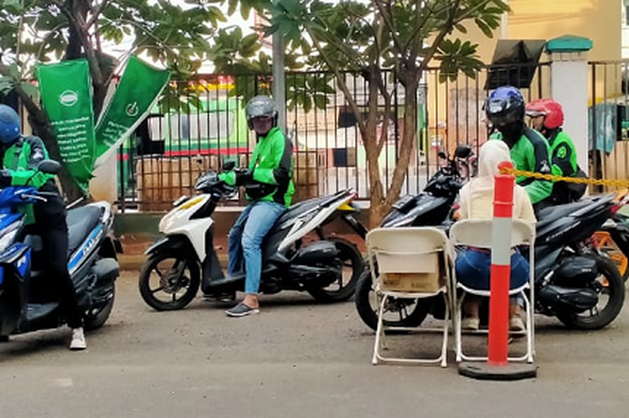 Driver gojek cek suhu dan penyemprotan disinfektan.