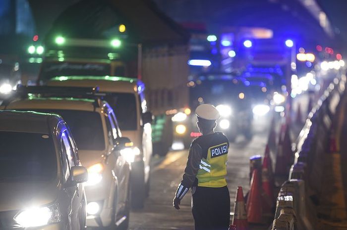 Petugas kepolisian mengarahkan kendaraan pribadi yang melintas di tol Jakarta-Cikampek untuk keluar melalui pintu tol Cikarang Barat 3, Jawa Barat, Kamis (21/5/2020)