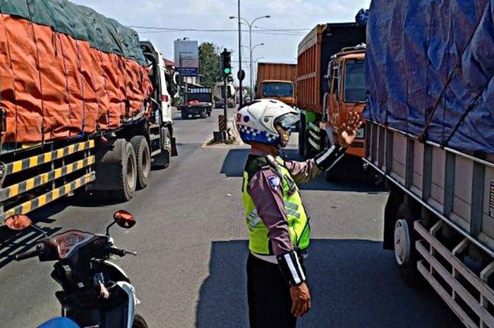 Personel Polsek Genuk mengatur arus lalu lintas di Kaligawe Semarang yang tersendat lantaran naiknya air rob di kawasan Sayung Demak, Selasa (9/6/2020). 