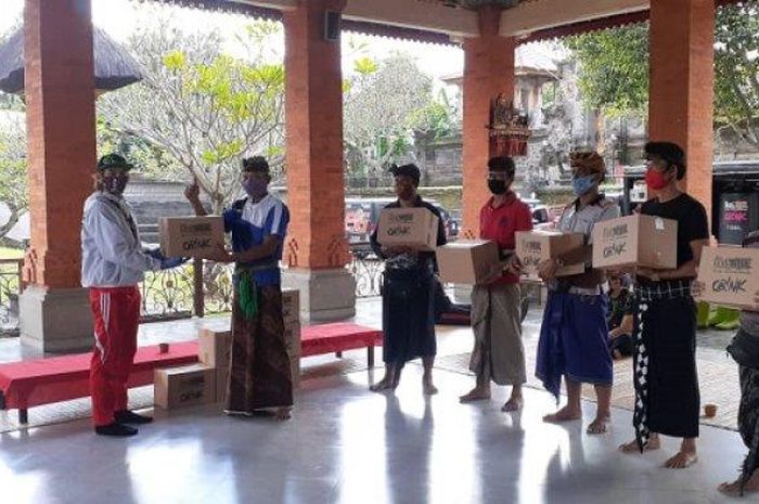 Team Bali MX membagikan masker kepada warga desa serta melakukan penyemprotan disinfektan keliling di Desa Sempidi, Badung