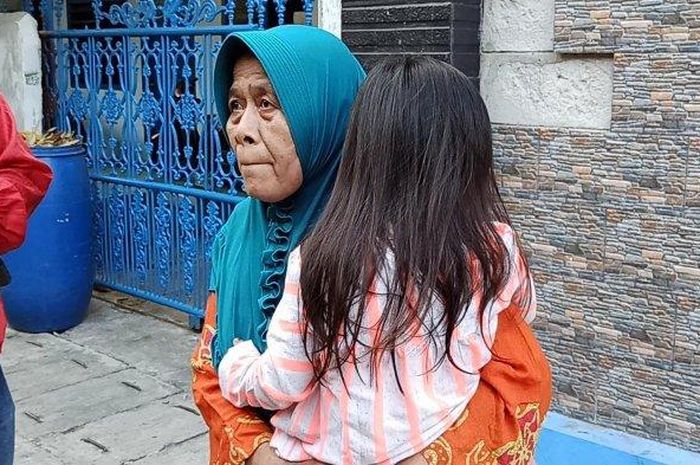 Inah (63) saat menggendong cucunya yang menjadi korban penjambretan di Jalan Swasembada XII, Tanjung Priok, Jakarta Utara, Selasa (30/6/2020). 