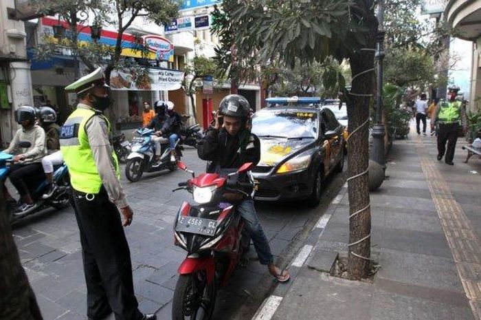 Petugas Polrestabes Bandung memberhentikan seorang pengendara sepeda motor yang melewati Jalan Braga, Kota Bandung tanpa menggunakan masker, Sabtu (11/07/2020).