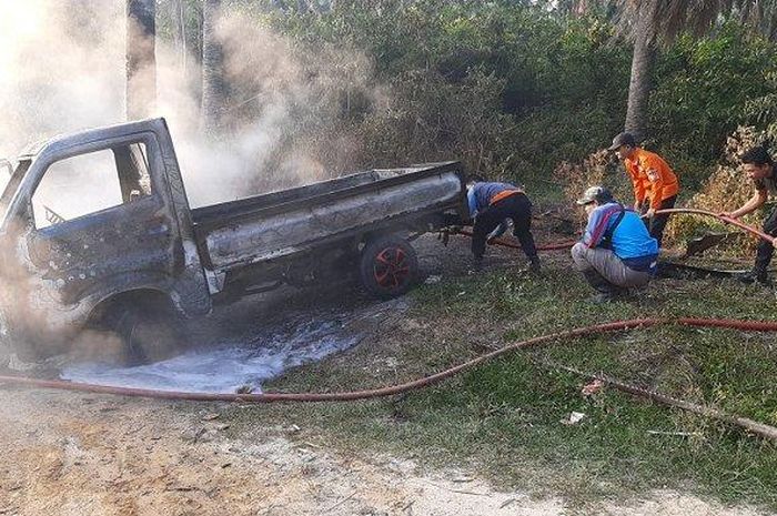 Petugas pemadam BPBD Langsa saat memadamkan api mobil Suzkui Carry jenis pikup yang diparkir di sekitar perkebunan kelapa sawit PT Timbang Langsa. 