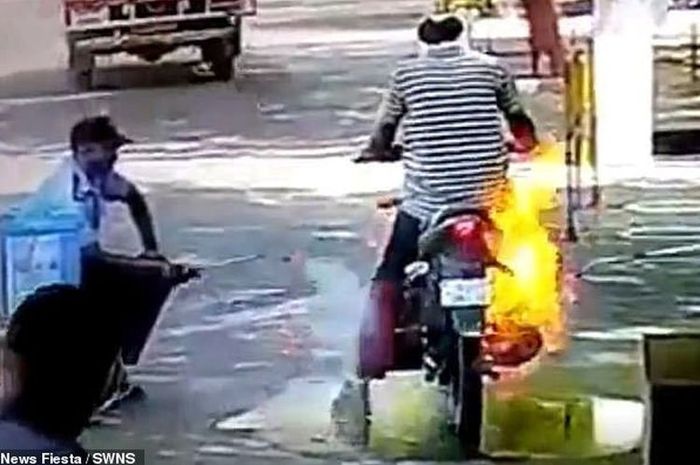 Api menjalar di sepeda motor seorang pria ketika disemprot disinfektan.