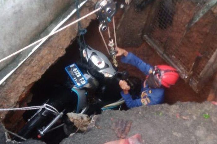 Proses pengangkatan Honda Supra Fit yang tercebur ke dalam lubang septic tank di Gang Dahlia, Balekambang, Kramat Jati, Jakarta Timur, (21/7/20) sore. 