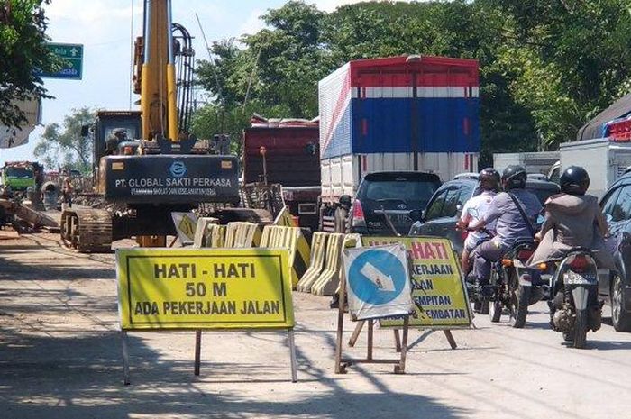 Para pengguna jalan melintasi lokasi proyek perbaikan geometrik jalan di Simpang Hanoman, Senin (20/7/2020)