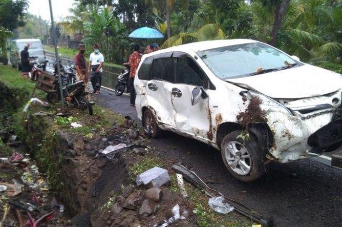 Toyota Avanza dievakuasi usai pecah ban lalu hajar Honda Supra dan berakhir tertancap ke got di desa Gumbrih, Pekutatan, Jembrana, Bali